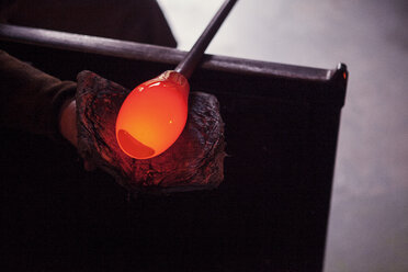 Ausgeschnittenes Bild eines Handwerkers, der eine Glasmacherpfeife mit geschmolzenem Glas in der Werkstatt hält - CAVF07777