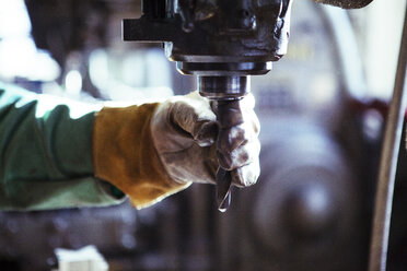 Ausgeschnittenes Bild eines Arbeiters, der eine Bohrmaschine in einer Werkstatt einstellt - CAVF07780