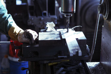 Ausgeschnittenes Bild eines Arbeiters, der eine Bohrmaschine in einer Werkstatt bedient - CAVF07782