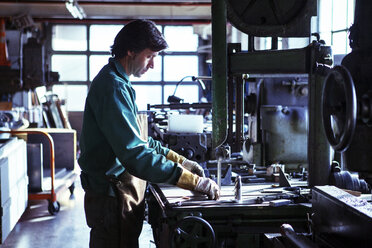 Seitenansicht eines Mannes bei der Arbeit in einer Werkstatt - CAVF07787
