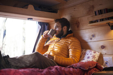 Man having drink while sitting in camper van - CAVF07790