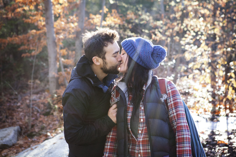 Zärtliches Paar, das sich küsst, während es auf einem Feld steht, lizenzfreies Stockfoto