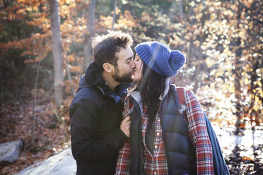 Affectionate couple kissing while standing on field - CAVF07797