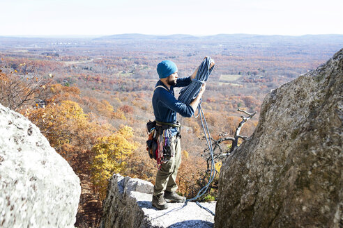 Mann hält Kletterseil, während er auf einem Felsen steht - CAVF07812
