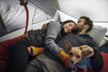 Mann küsst Freundin auf die Stirn, während er im Zelt entspannt - CAVF07828