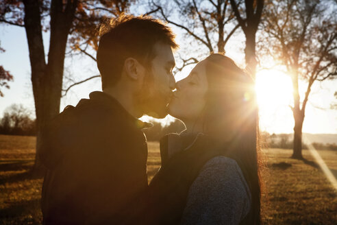 Seitenansicht eines zärtlichen Paares, das sich küsst, während es auf einem Feld steht - CAVF07844