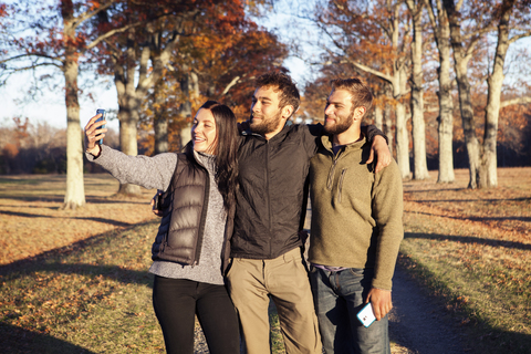 Freunde machen ein Selfie, während sie auf dem Feld stehen, lizenzfreies Stockfoto