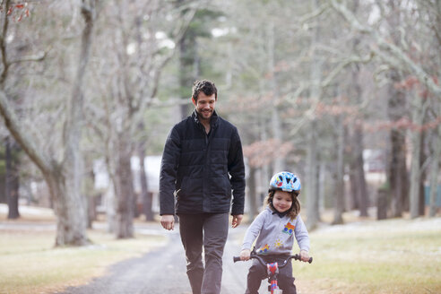 Glücklicher Vater sieht seinen Sohn beim Fahrradfahren auf der Straße an - CAVF07875