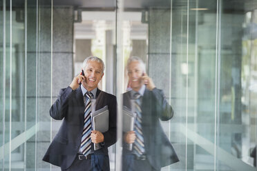 Businessman talking on cell phone in office building - CAIF15744