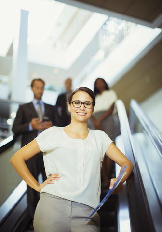 Geschäftsfrau auf Rolltreppe in Bürogebäude, lizenzfreies Stockfoto