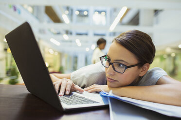 Businesswoman relaxing with laptop in office building - CAIF15760