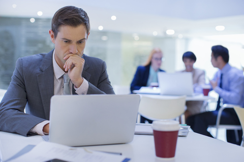 Geschäftsmann arbeitet am Laptop am Tisch, lizenzfreies Stockfoto