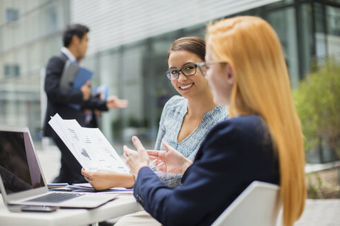 Businesswomen looking at documents at table in office building - CAIF15775