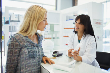 Woman discussing product with pharmacist in drugstore - CAIF15811