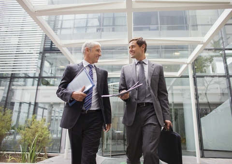 Geschäftsleute gehen gemeinsam aus einem Bürogebäude heraus, lizenzfreies Stockfoto