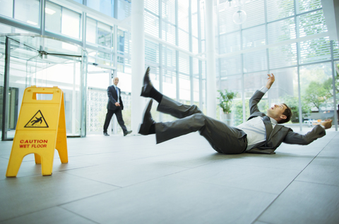 Geschäftsmann rutscht auf dem Boden eines Bürogebäudes aus, lizenzfreies Stockfoto