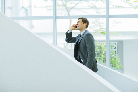 Geschäftsmann, der auf der Treppe eines Bürogebäudes mit seinem Handy telefoniert, lizenzfreies Stockfoto