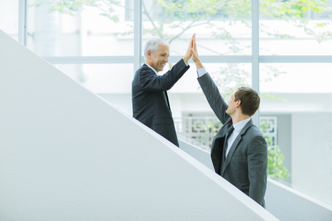 Geschäftsleute, die sich auf der Treppe eines Bürogebäudes die Hände reichen, lizenzfreies Stockfoto