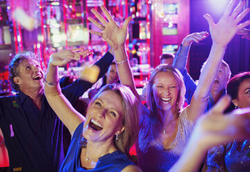 Menschen heben die Hände und lachen in einem Nachtclub - CAIF15834