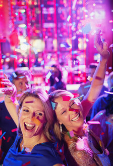 Confetti falling on two women dancing back to back in nightclub - CAIF15835