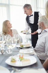 Kellner serviert einer Frau am Restauranttisch ein schickes Gericht - CAIF15844
