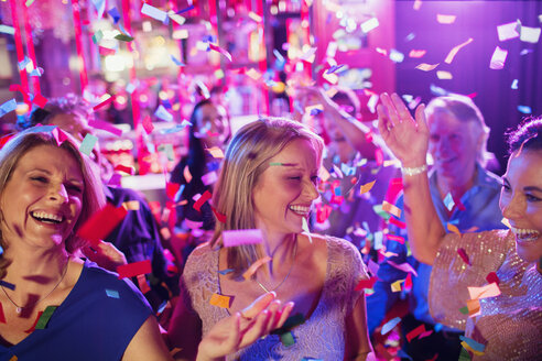 Confetti falling on smiling mature women dancing in nightclub - CAIF15850