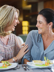 Zwei Freundinnen unterhalten sich und lachen im Restaurant, schickes Geschirr auf dem Tisch - CAIF15852