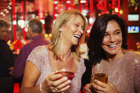 Zwei lächelnde reife Frauen, die in einem Nachtclub Getränke genießen, lizenzfreies Stockfoto