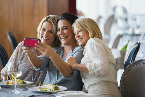 Drei reife Frauen nehmen Selfie im Restaurant, lizenzfreies Stockfoto