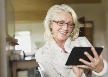 Lächelnde ältere Frau mit digitalem Tablet - CAIF15871