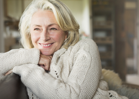 Lächelnde ältere Frau im Pullover schaut weg, lizenzfreies Stockfoto