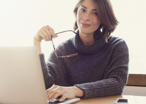 Porträt selbstbewusste brünette Frau mit Brille und Laptop, lizenzfreies Stockfoto