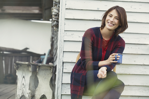 Porträt lächelnde brünette Frau trinkt Kaffee auf Veranda, lizenzfreies Stockfoto