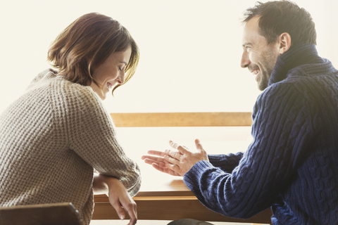 Laughing couple in sweaters at table stock photo