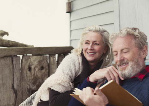 Smiling senior couple reading book on patio stock photo