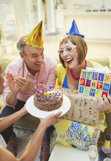 Lächelnde reife Frauen erhalten Geburtstagskuchen und Geschenke - CAIF15927