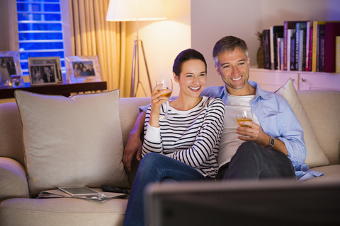 Ehepaar trinkt Wein und sieht im Wohnzimmer fern, lizenzfreies Stockfoto