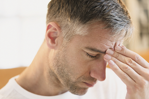 Nahaufnahme eines Mannes mit Kopfschmerzen, der die Stirn berührt, lizenzfreies Stockfoto