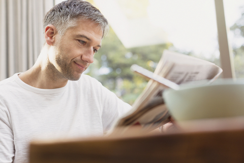 Mann liest beim Frühstück Zeitung, lizenzfreies Stockfoto