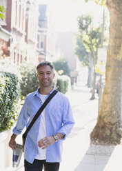 Portrait smiling businessman walking on sidewalk - CAIF15969