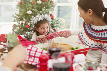 Mutter und Tochter ziehen beim Abendessen an einem Weihnachtsgebäck - CAIF15973