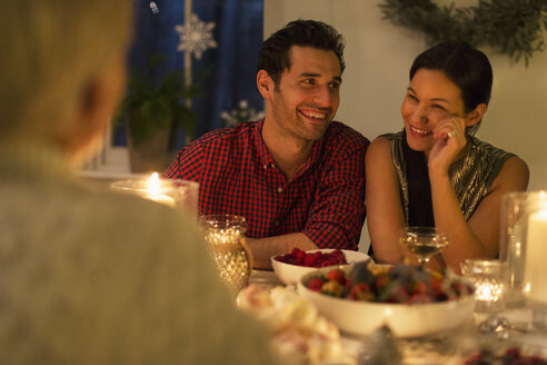 Lächelndes Paar genießt Weihnachtsessen bei Kerzenschein - CAIF15975