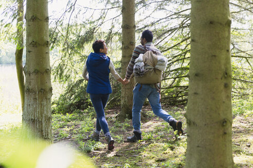 Couple holding hands and hiking with backpack in woods - CAIF15999