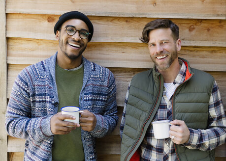 Portrait smiling men drinking coffee outside cabin - CAIF16010