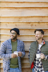 Lächelnde Männer trinken Kaffee vor der Hütte - CAIF16018