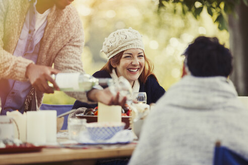 Friends drinking wine enjoying lunch at patio table - CAIF16022