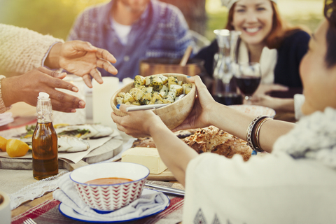 Friends passing food across patio lunch table stock photo