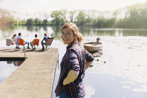 Portrait smiling woman at sunny lakeside dock - CAIF16027
