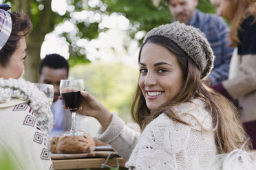 Porträt einer lächelnden Frau, die beim Mittagessen mit Freunden im Innenhof Wein trinkt - CAIF16029