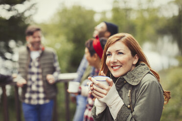 Smiling woman drinking coffee on balcony - CAIF16062